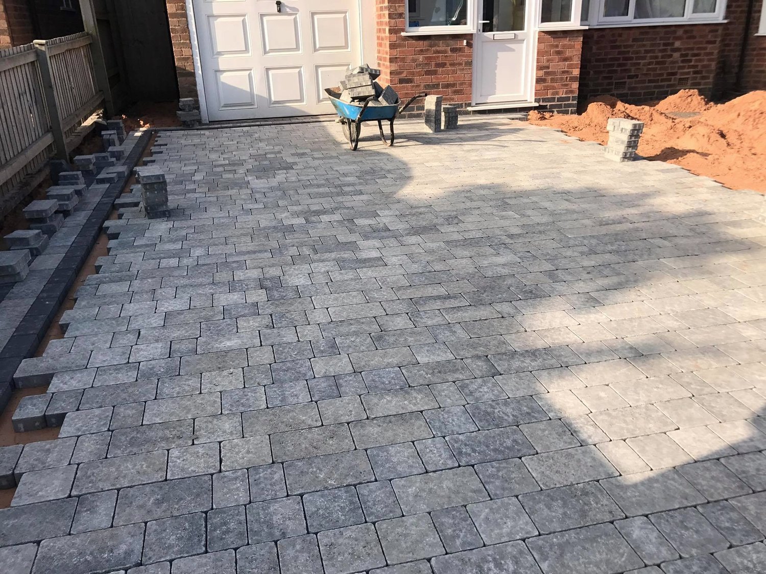 Block paving mid install with stacked blocks and wheelbarrow