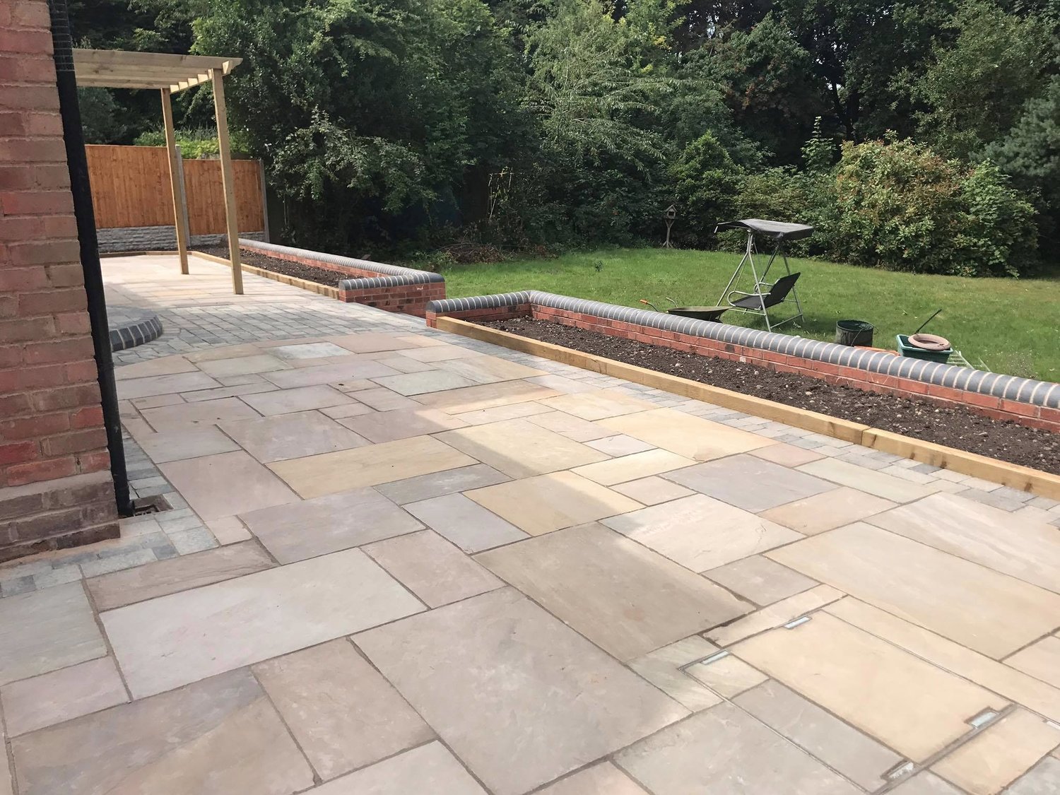 Indian sandstone patio with brick raised beds and pergola